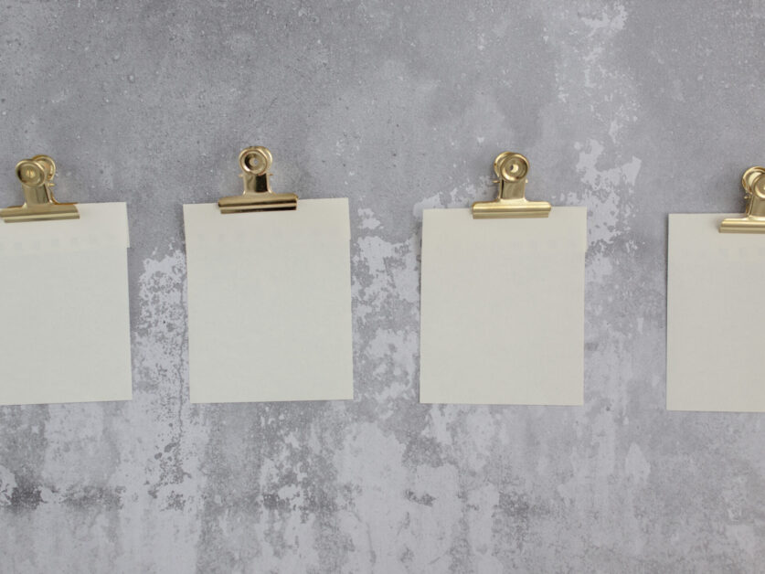 Blank stickers for notes attached with gold holders and hung on gray wall