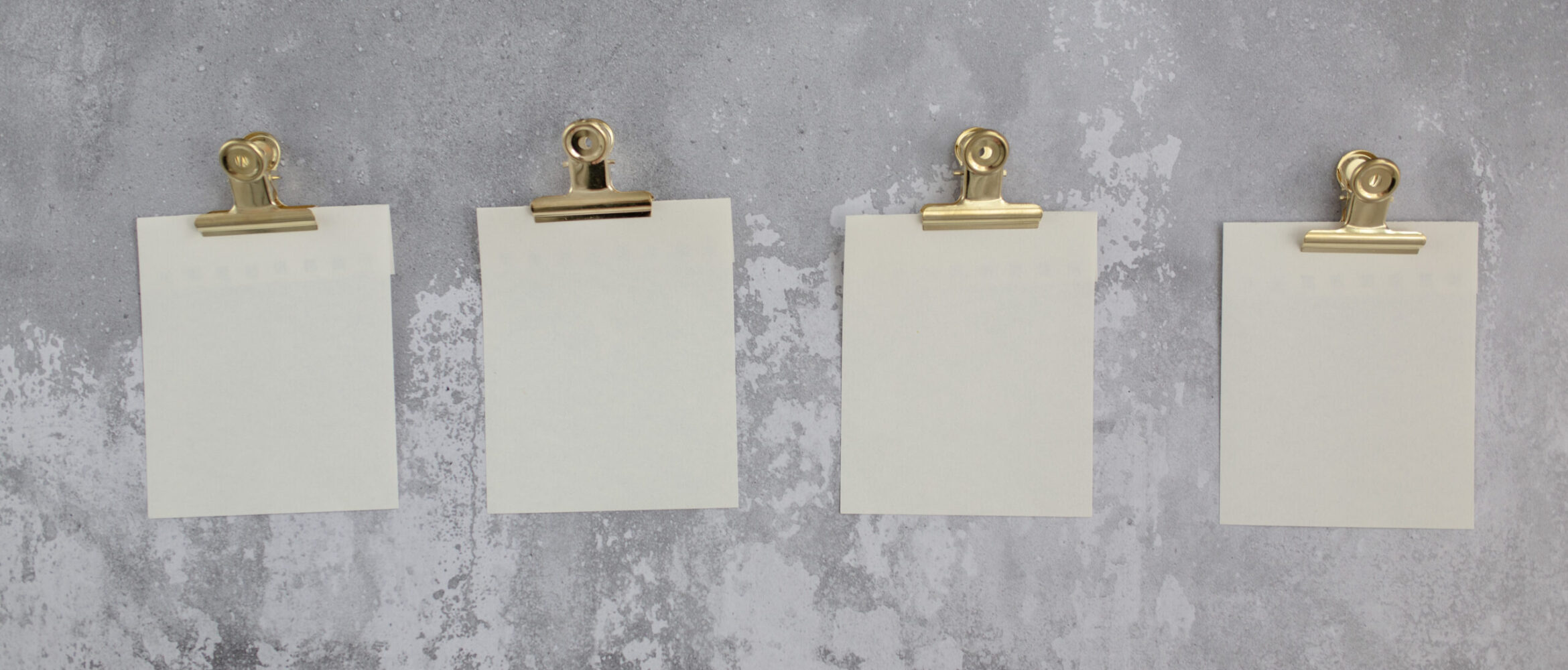 Blank stickers for notes attached with gold holders and hung on gray wall