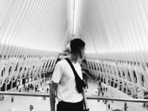 Black and white of young guy with waist bag admiring geometric ceiling of contemporary building